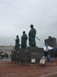 高知県の高知市、高知駅前の観光広場「こうち旅広場」に位置する「土佐三志士像」。日本の近代国家への第一歩に大きく尽力した、幕末の志士、武市半平太（たけちはんぺいた）、坂本龍馬、中岡慎太郎の銅像が堂々と並んでいます。
