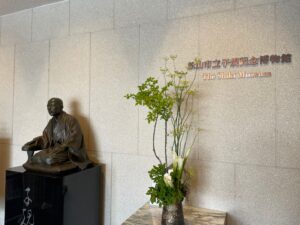松山市立子規記念博物館入口には子規像とウエルカム生花が出迎えてくれます
